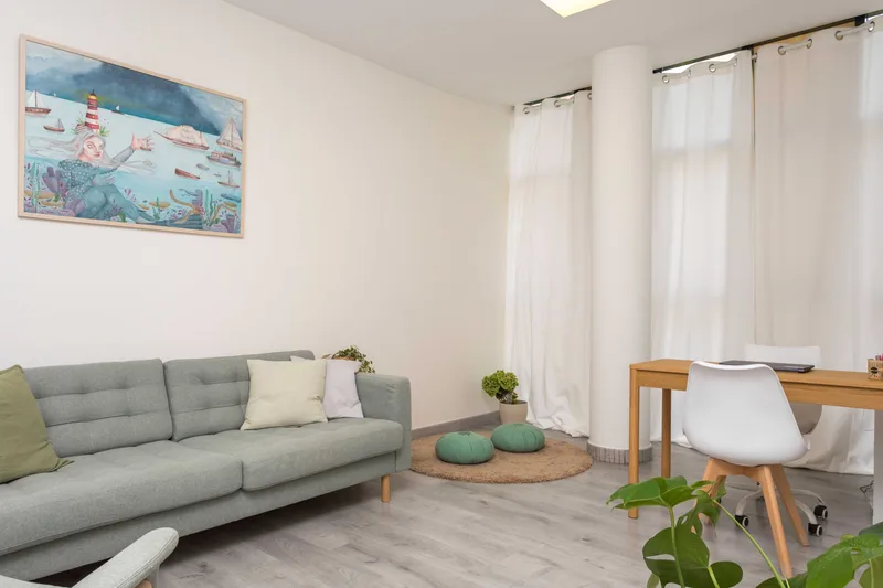 Consulta con sofá verde, escritorio y cojines de meditación